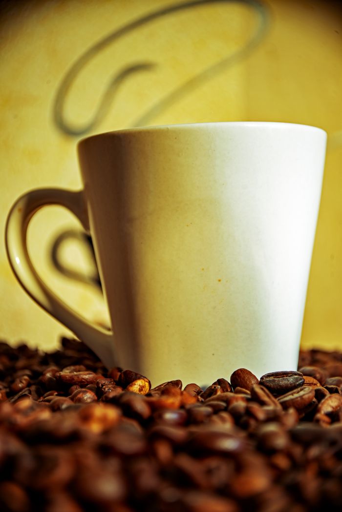 About A white coffee mug surrounded by aromatic coffee beans, perfect for a cozy ambiance.
